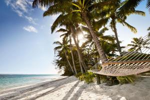 a hammock on a beach with palm trees at Motu Beachfront Art Villas in Rarotonga