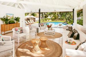 a living room with a table and chairs and a pool at Motu Beachfront Art Villas in Rarotonga