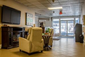 a living room with chairs and a television and a table at Northwood Plaza Hotel in Prince George