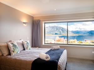 a bedroom with a large window with a view of the water at Hotel Lake Brunner in Moana
