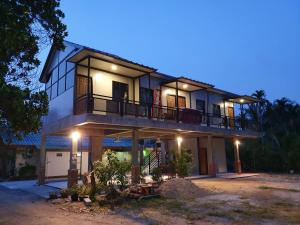 uma casa grande com uma varanda à noite em Green Happy Homestay em Phatthalung