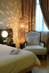 - une chambre avec un lit, une chaise et une lampe dans l'établissement Tanjung Villa, à Muar