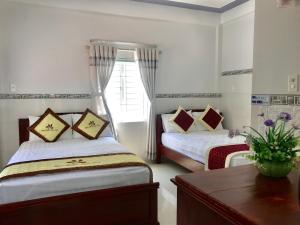 una camera con due letti, un tavolo e una finestra di NGỌC QUÝ Mini House a Quy Nhon