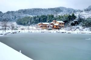 a snow covered lake with a house in the background at Dayong Antique Feature Resort in Zhangjiajie