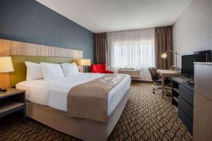 a hotel room with a large bed and a television at Days Inn & Suites by Wyndham Rochester Hills MI in Rochester Hills +29 photos