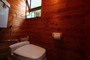 a bathroom with wooden walls and a toilet and a window at Gokase Campsite Camping and Guesthouse in Gokase