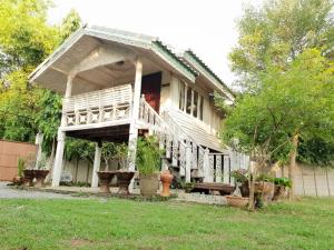 Baan Suan Yensabai @Ayutthaya في فرا ناخون سي أيوتثايا: منزل به شرفة مع نباتات الفخار