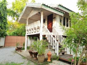 uma casa branca com uma escada e vasos de plantas em Baan Suan Yensabai @Ayutthaya em Phra Nakhon Si Ayutthaya
