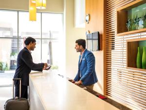 two men standing at a counter in an office at ibis Deira Creekside Dubai in Dubai
