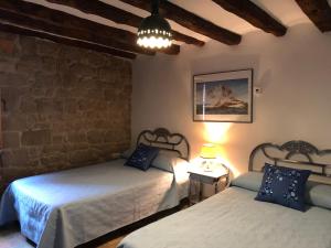 a bedroom with two beds and a stone wall at Solano de Moran in Murillo de Gállego
