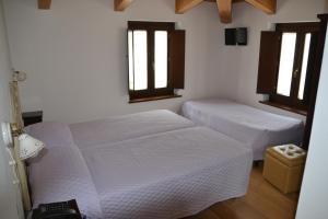 two beds in a room with two windows at Agriturismo Antico Muro in Sassoferrato +22 photos