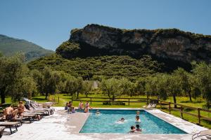 een groep mensen in een zwembad met een berg op de achtergrond bij O_live Agriresort in Arco