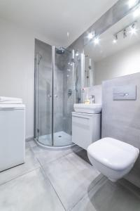 La salle de bains blanche est pourvue d'une douche et de toilettes. dans l'établissement Apartament Sobieskiego 2a Parking gratiss, à Bydgoszcz