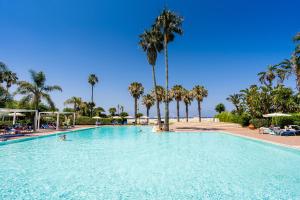 uma grande piscina com palmeiras num resort em Le Dune Beach Club em Torre Faro