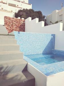 a swimming pool with stairs and blue tiles on a building at Alojamientos 4nudos in San José