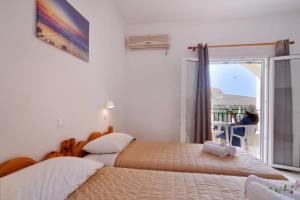 two beds in a bedroom with a view of the ocean at Makris Apartments Arillas Corfu in Arillas
