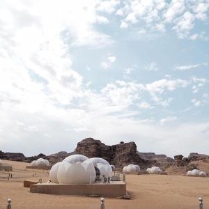 eine Gruppe von Kuppeln in der Wüste unter einem wolkigen Himmel in der Unterkunft Wadi Rum Bubble Luxotel in Wadi Rum