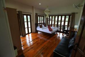 sala de estar con cama, suelo de madera y ventanas en Hotsia Homestay en Ban Pak Ing