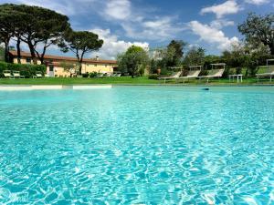 a pool of blue water with chairs in the background at Borgo Casalvento in Cantagrillo