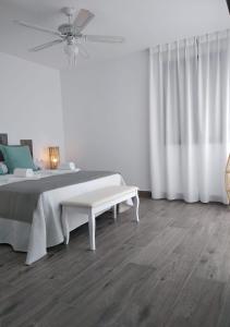 a white bedroom with a bed and a bench at Alojamientos 4nudos in San José