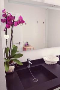 a bathroom with a sink with a vase with purple flowers at Alojamientos 4nudos in San José