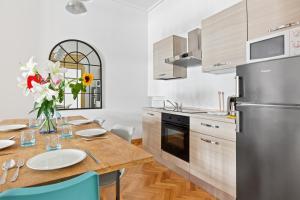 uma cozinha com uma mesa de madeira e um frigorífico de aço inoxidável em Roomy Apartment Duomo & San Babila em Milão
