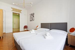 um quarto com uma grande cama branca com duas toalhas em Roomy Apartment Duomo & San Babila em Milão