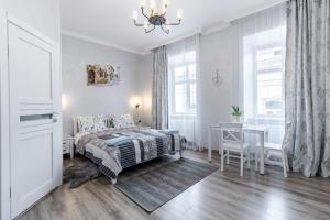 a white bedroom with a bed and a table at Golden Rose ! Apartments Lviv in Lviv