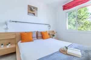 エンプリアブラバにあるGoldhome - Bahia 6のベッドルーム1室(オレンジ色の枕と窓付)