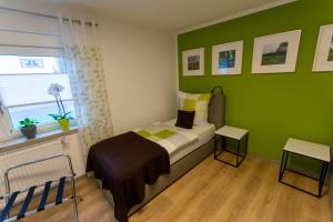 1 dormitorio con paredes verdes, 1 cama y ventana en Fewo Lindenstrasse en Großrudestedt