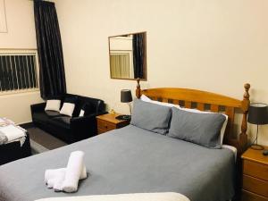 - une chambre avec un lit, une chaise et un miroir dans l'établissement Otautau Hotel, à Otautau
