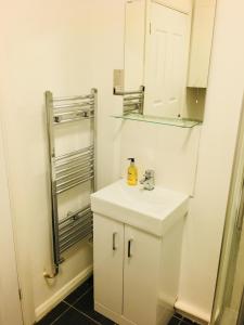 ein weißes Badezimmer mit einem Waschbecken und einem Spiegel in der Unterkunft Fountain View 1BR Flat Oxford - Free Parking in Oxford