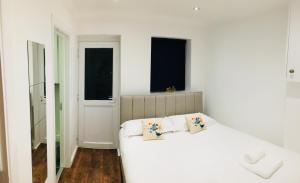 a white bedroom with a bed and two windows at Fountain View 1BR Flat Oxford - Free Parking in Oxford