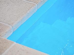 a swimming pool with blue water and a brick wall at 14 person holiday home in Idestrup in Marielyst