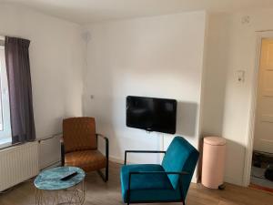 a living room with two chairs and a tv on the wall at Bij Frits in Zandvoort