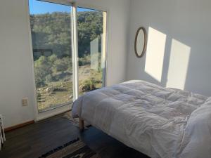 a bedroom with a bed and a large window at GUIDAI in Villa Serrana