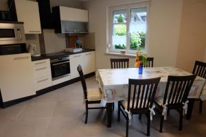 uma cozinha com mesa e cadeiras e uma cozinha com armários brancos em Ferienhaus am Wald em Bad Elster