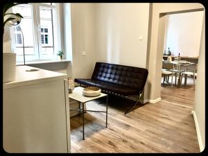 a black leather couch in a living room with a table at Apartamenty 8 in Poznań