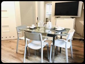 comedor con mesa de cristal y sillas blancas en Apartamenty 8, en Poznan