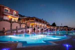 una piscina por la noche con un edificio en el fondo en Dionysos Village Resort, en Lassi