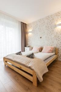 Un dormitorio con una gran cama de madera con almohadas rosas en Vintage Krasińskiego 7 Apartments en Cracovia