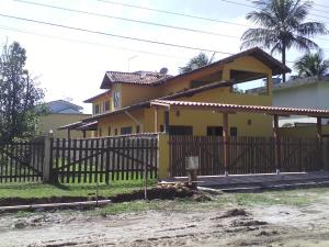 a yellow house with a fence in front of it at Makitub in Boracéia