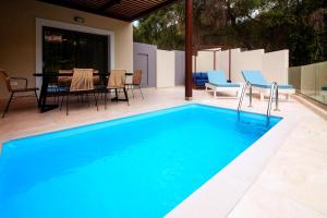 una piscina con mesa y sillas junto a ella en Elite Luxury Villas en Parga