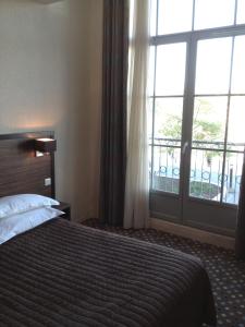 a bedroom with a bed and a large window at LES ARCADES in Dieppe