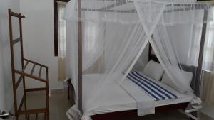 a bedroom with a canopy bed and a chair at Kalpa Place Hiriketiya in Hiriketiya