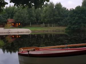 un bateau assis sur l'eau devant une maison dans l'établissement Ło'Burka, à Chrztowo