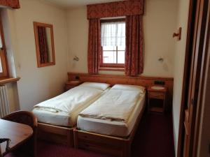 two beds in a small room with a window at Garni Baita Cecilia in Livigno