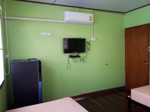 a room with a green wall with a tv on the wall at Punnpannsuk in Trat