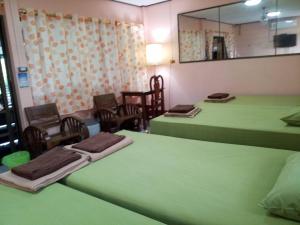 a room with two green beds and a mirror at Punnpannsuk in Trat