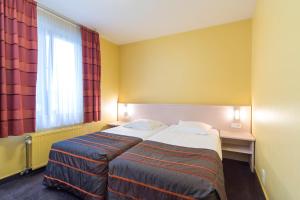 una camera d'albergo con letto e finestra di Hotel Leo Station, Villa et Annexes a Bastogne